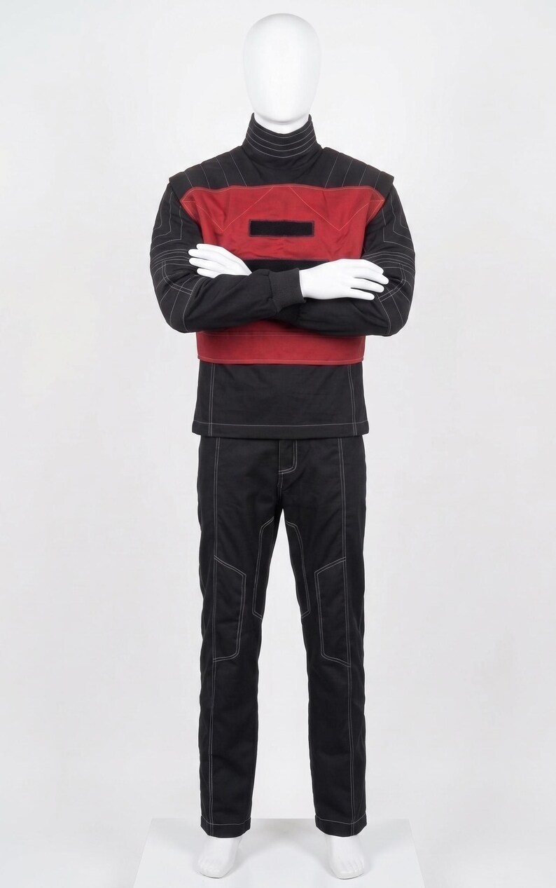 May include: A black long-sleeved shirt with a high collar and a red chest panel featuring a rectangular black patch. The shirt has white contrast stitching throughout. Matching black trousers with white contrast stitching are worn with the shirt.