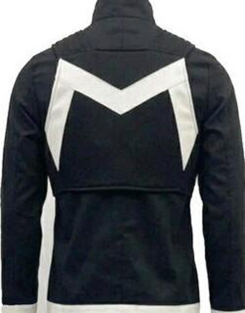 May include: A black jacket featuring a high collar and long sleeves. The back of the garment displays a prominent white chevron-shaped design across the upper section, with a straight white band along the bottom hemline of the jacket.