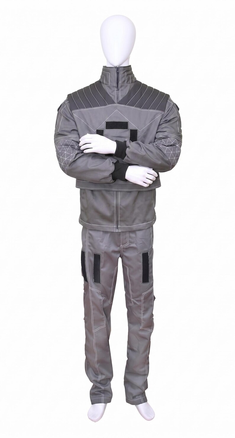May include: A gray two-piece uniform set consisting of a long-sleeved jacket and matching trousers. The jacket features a high collar, dark gray shoulder panels with white stitching, and black rectangular accents. The sleeves have a geometric pattern.