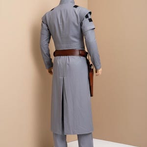 May include: A set of three ceramic mugs with a speckled, matte finish. The mugs are in shades of cream, light gray, and dark gray. Each mug has a simple, minimalist design and a rounded handle. The mugs are likely for coffee or tea.