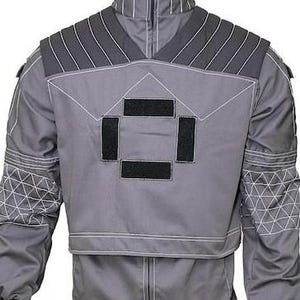 May include: A grey tactical-style jacket featuring a high collar, dark grey ribbed shoulder panels, and four rectangular black hook-and-loop patches on the chest. The sleeves display a white geometric grid pattern, and white contrast stitching.