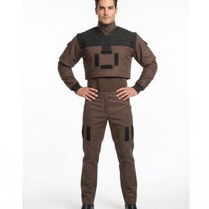 May include: A brown and black costume consisting of a turtleneck top, cropped vest, and pants. The vest has a geometric design, and the pants have black patches. The costume is completed with black boots.