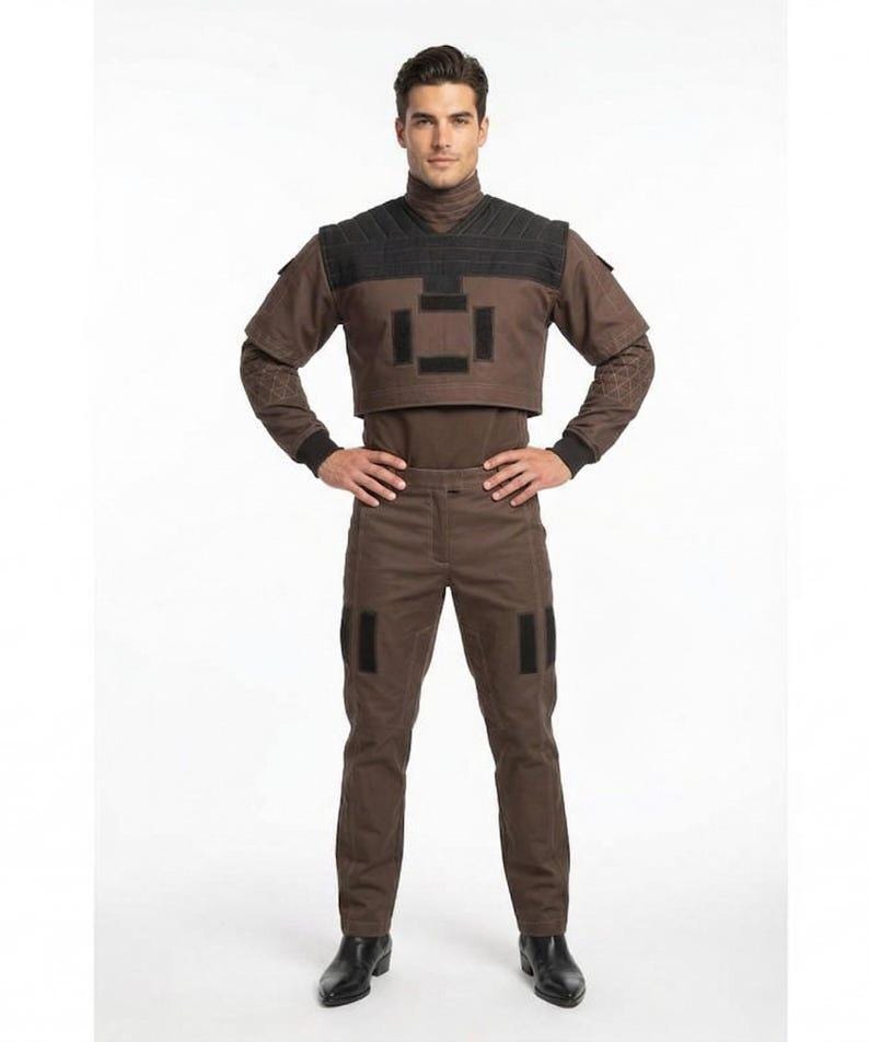 May include: A brown and black costume consisting of a turtleneck top, cropped vest, and pants. The vest has a geometric design, and the pants have black patches. The costume is completed with black boots.