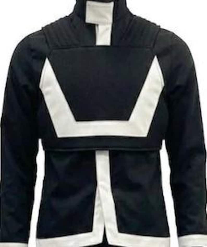 May include: A black long-sleeve jacket featuring a high collar with a white vertical stripe, a white U-shaped chest panel, and white trim along the bottom hem and cuffs. The garment has a structured design with ribbed shoulder detailing.