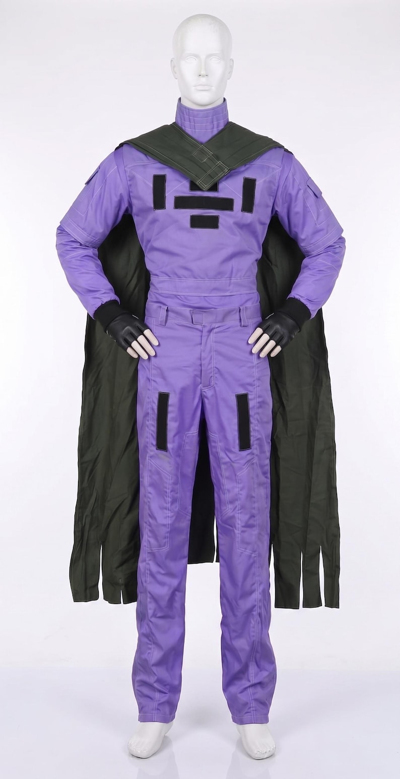 May include: A purple jumpsuit with long sleeves and a high collar, featuring black rectangular patches on the chest and thighs. The outfit includes a dark olive green cape draped over the shoulders and black gloves, worn on a white mannequin figure.