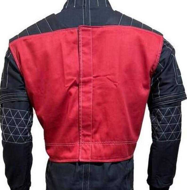 May include: A black jacket featuring a prominent red panel on the back, white contrast stitching throughout, and a geometric triangular pattern on the sleeves. The garment includes a vertical center seam and structured shoulder detailing.