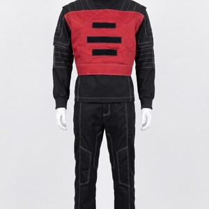 May include: A black long-sleeved shirt with a high collar and white contrast stitching, paired with matching black trousers. A red chest panel is layered over the shirt, featuring three horizontal black rectangular patches on the front.