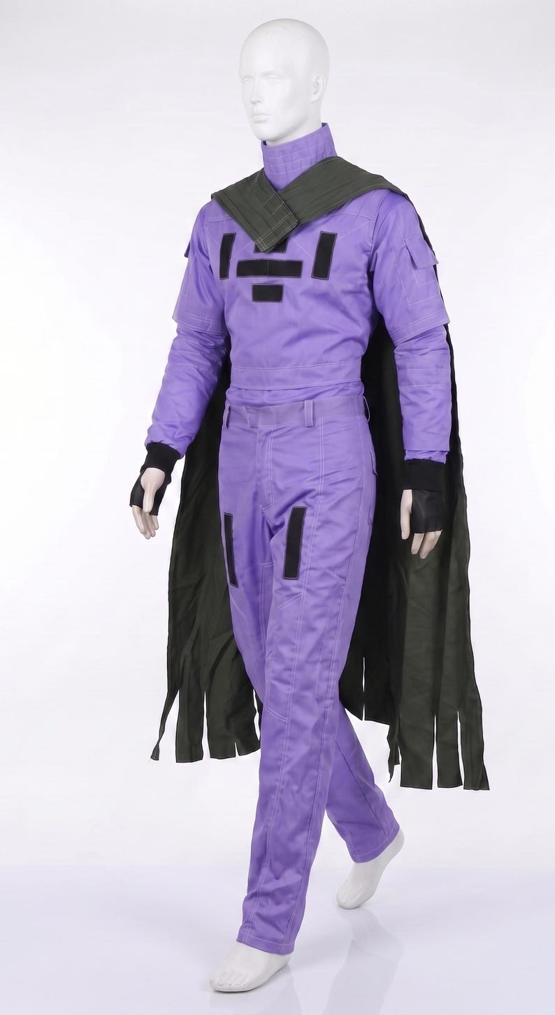May include: A purple long-sleeved jumpsuit featuring a high collar, black rectangular chest patches, and black fingerless gloves. A dark olive green cape with a textured shoulder yoke and a fringed hem drapes over the shoulders of the mannequin.