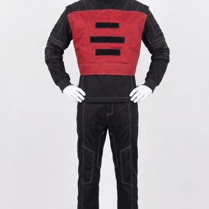 May include: A black long-sleeved mock neck shirt and matching trousers featuring white contrast stitching throughout. The outfit includes a red chest panel with three horizontal black rectangular patches across the front center.