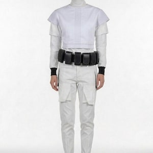 Pu&ograve; includere: Un outfit in stile futuristico bianco, composto da un top a collo alto, una giacca corta e pantaloni cargo. Una cintura nera con tasche e stivali neri completano l'ensemble. L'outfit ha un'estetica pulita e minimalista, adatta al cosplay.