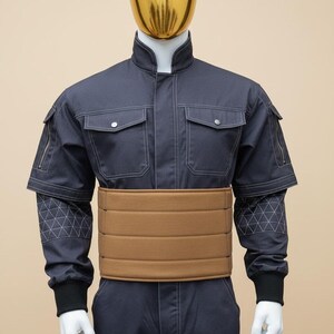 May include: A mannequin wearing a dark blue jumpsuit with a brown belt. The jumpsuit has pockets, zippers, and white stitching. The mannequin has a gold-coloured head.