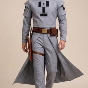 May include: A gray costume with black accents, featuring a high collar, long sleeves, and a long coat-like extension. The outfit includes a brown belt, holster, and a matching leg strap. The pants have quilted details, and the boots are gray and brown.