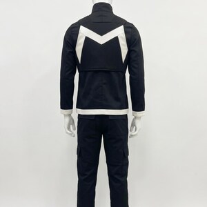 May include: A black jacket and matching trousers set featuring a white M-shaped emblem on the back of the jacket. The jacket has a high collar and white trim at the hem and cuffs. The trousers are long with side cargo pockets and white accents.
