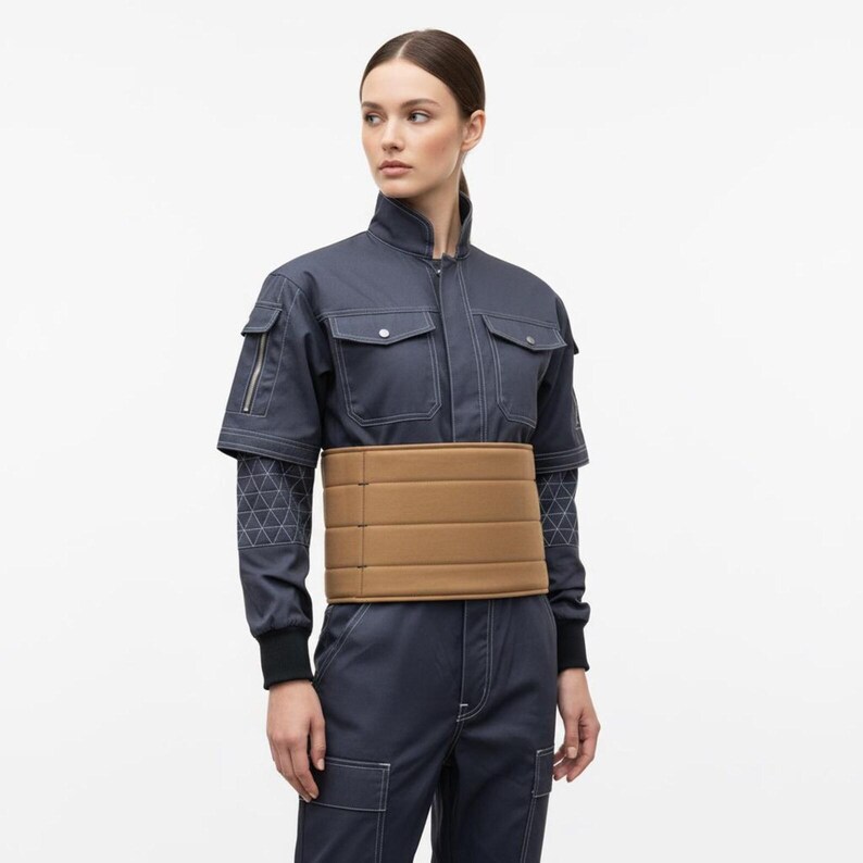 May include: A navy blue jumpsuit with white stitching and a tan belt. The jumpsuit features short sleeves, multiple pockets, and a zip closure. The belt is made of a padded material and wraps around the waist.