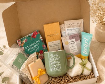 Puede incluir: Una caja de regalo que contiene una taza verde con texto blanco, una barra de chocolate amarilla, un libro floral titulado Meaningful Moments with God, un kit de pedicura, un tubo de crema Pearl Glow, un jabón con cinta amarilla y sales de baño.