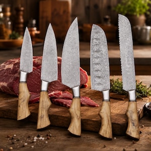 May include: A set of five kitchen knives with wooden handles and patterned blades. The knives are arranged in front of a wooden cutting board with a large piece of raw meat. The blades have a silver finish.