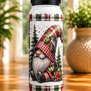 May include: White insulated water bottle with a black handle and lid. The bottle features a festive gnome design with a red and green plaid pattern, Christmas trees, and a red poinsettia. The top and bottom have a matching plaid border.