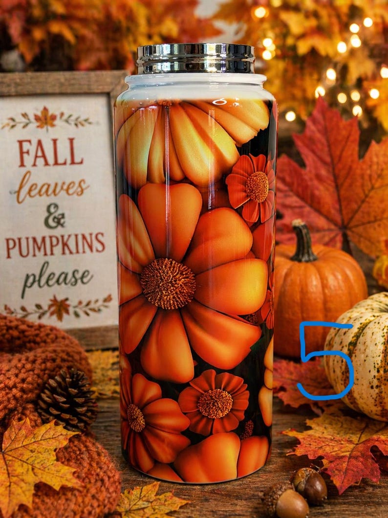 May include: A stainless steel water bottle with a floral design in shades of orange and yellow. The bottle features large, stylized flowers and smaller blossoms. The words "FALL leaves & PUMPKINS please" are visible on a wooden sign.