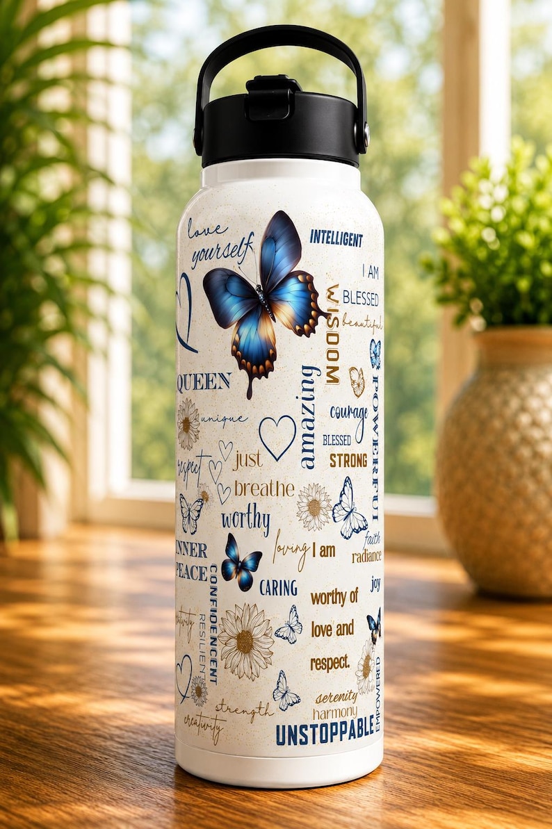 Puede incluir: Botella de agua blanca con asa y tapa negras, decorada con mariposas azules y palabras inspiradoras como "&aacute;mate" e "imparable". La botella tiene un asa y una tapa negras.
