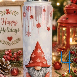 K&ouml;nnte beinhalten: Eine wei&szlig;e isolierte Wasserflasche mit silbernem Deckel und festlichem Design. Die Flasche zeigt einen Wichtel mit roter M&uuml;tze mit wei&szlig;en Sternen, Schneeflocken und dem Schriftzug "Happy Holidays" auf einem Schild im Hintergrund.