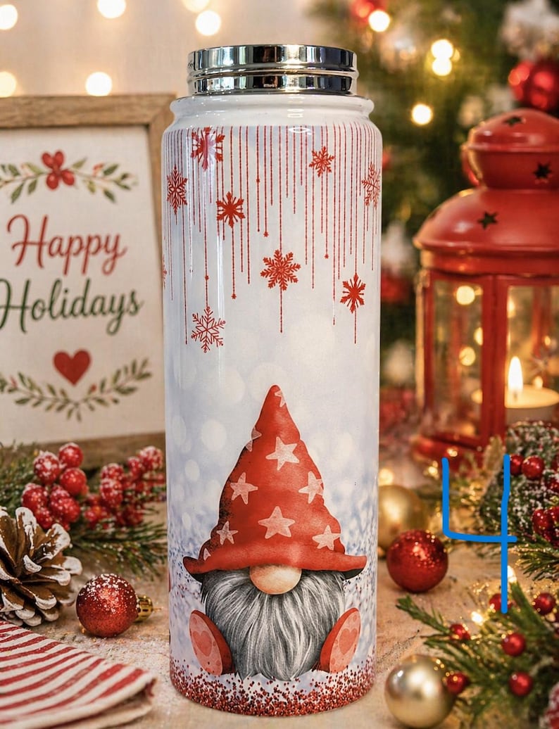 K&ouml;nnte beinhalten: Eine wei&szlig;e isolierte Wasserflasche mit silbernem Deckel und festlichem Design. Die Flasche zeigt einen Wichtel mit roter M&uuml;tze mit wei&szlig;en Sternen, Schneeflocken und dem Schriftzug "Happy Holidays" auf einem Schild im Hintergrund.