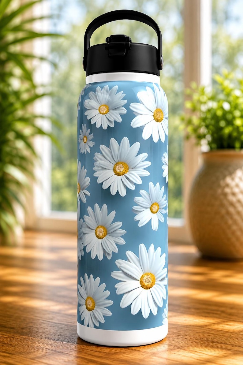 K&ouml;nnte beinhalten: Eine Edelstahl-Wasserflasche mit hellblauem Hintergrund und einem Muster aus wei&szlig;en G&auml;nsebl&uuml;mchen mit gelben Zentren. Die Flasche hat einen schwarzen Griff und Deckel sowie einen wei&szlig;en Boden. Ideal f&uuml;r die Fl&uuml;ssigkeitszufuhr.