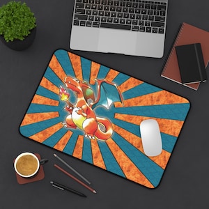 May include: A rectangular mousepad featuring a cartoon Charizard character with orange and yellow flames, blue wings, and a yellow belly. The background has an orange and blue sunburst design. A white mouse and a laptop are also visible.