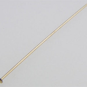 May include: A gold-colored head pin with a flat, round head. The pin is about 1.5 inches long.