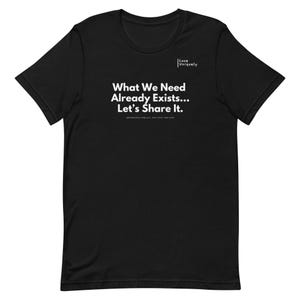 May include: Black t-shirt with the white text "What We Need Already Exists... Let's Share It." The shirt also features the "Love Uniquely" logo in white. The text "Abundance for all, not just for few" is printed below the main text.