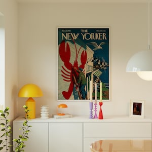 Puede incluir: Una portada enmarcada de la revista "The New Yorker" con una ilustraci&oacute;n de langosta roja. La portada incluye una escena costera con una gaviota y el texto "May 21, 1956".