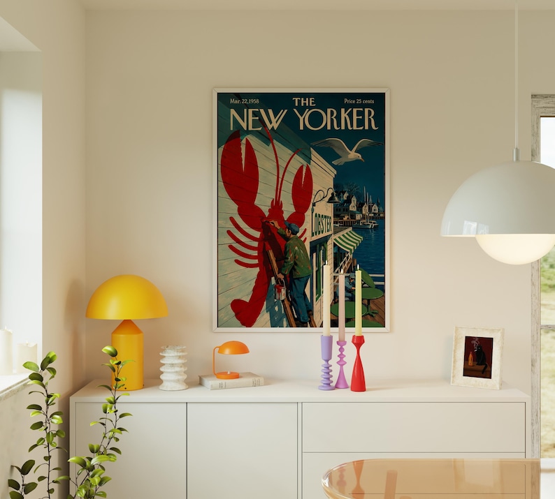 Puede incluir: Una portada enmarcada de la revista "The New Yorker" con una ilustraci&oacute;n de langosta roja. La portada incluye una escena costera con una gaviota y el texto "May 21, 1956".