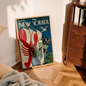 Puede incluir: Una portada enmarcada de la revista The New Yorker con una ilustraci&oacute;n de una langosta roja. La portada muestra una escena costera con una gaviota, un restaurante y el texto "The New Yorker". El marco es de color marr&oacute;n claro.