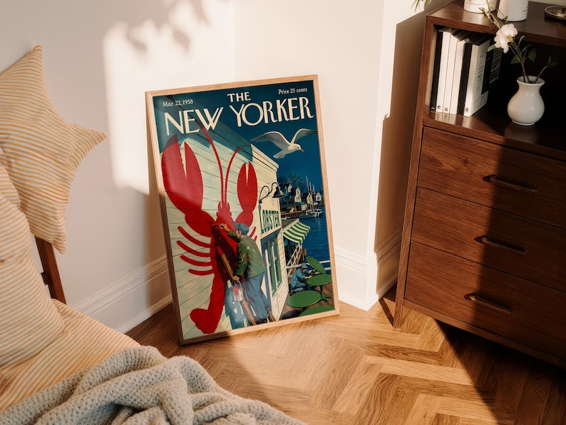 Puede incluir: Una portada enmarcada de la revista The New Yorker con una ilustraci&oacute;n de una langosta roja. La portada muestra una escena costera con una gaviota, un restaurante y el texto "The New Yorker". El marco es de color marr&oacute;n claro.