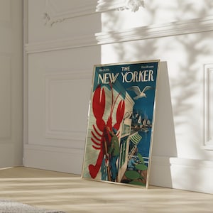 Puede incluir: Una portada enmarcada de la revista The New Yorker, con una langosta roja, una gaviota y una escena costera. El marco dorado se apoya en una pared blanca. El t&iacute;tulo de la revista es visible. El marco mide unos 30 cm de ancho.