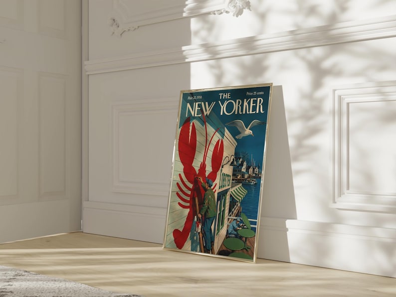 Puede incluir: Una portada enmarcada de la revista The New Yorker, con una langosta roja, una gaviota y una escena costera. El marco dorado se apoya en una pared blanca. El t&iacute;tulo de la revista es visible. El marco mide unos 30 cm de ancho.