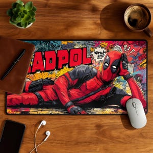 May include: Rectangular mousepad featuring a comic book style illustration of Deadpool in a red and black suit. The word "DEADPOOL" is in large, yellow letters. The background is a colorful collage of comic book elements.