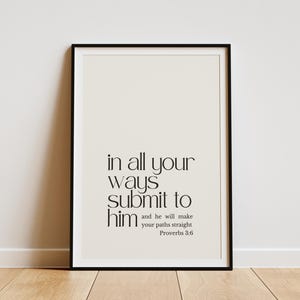 May include: A framed print with a black border, displaying the text "in all your ways submit to him and he will make your paths straight Proverbs 3:6" in a minimalist font. The background is a light cream colour.