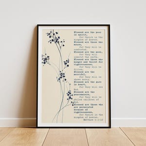 Può includere: Stampa incorniciata con testo da Matteo 5:3-10, su sfondo beige e in cornice nera. Il testo è in un carattere di macchina da scrivere. Delicati disegni floreali blu adornano il lato sinistro della stampa.
