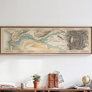 May include: A horizontal framed wall art print featuring a detailed topographical map of the Indus River. The map displays geographical terrain, river paths, and various labeled locations in a vintage style with beige, blue, and black ink tones.