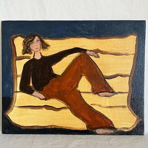 May include: An oil painting depicts a person reclining on a yellow surface against a dark blue background. The person wears a black top and rust-colored pants. The artwork has a minimalist style.