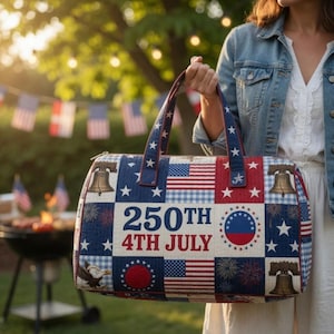 May include: A rectangular duffel bag featuring a patriotic patchwork design with red, white, and blue colors. The bag displays the text 250TH 4TH JULY, images of the Liberty Bell, American flags, fireworks, a bald eagle, and white stars.