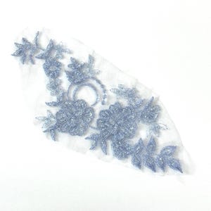 May include: A light blue floral lace applique with a delicate design. The lace is made of a sheer fabric and features a variety of floral motifs.