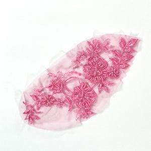 May include: Pink beaded floral applique with a delicate mesh backing. This embellishment features a floral design with leaves and intricate beadwork.