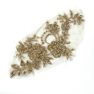 May include: Gold floral lace applique with sequins and beads. The applique is on a white mesh fabric.