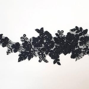May include: Black lace trim with a floral design. The lace is delicate and intricate, with small flowers and leaves.