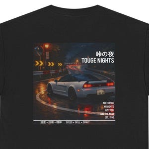May include: Black t-shirt featuring a graphic of a white sports car on a wet road at night. The design includes Japanese text and the words "TOUGE NIGHTS". Additional text reads "NO TRAFFIC, NO LIGHTS, JUST YOU AND THE ROAD".