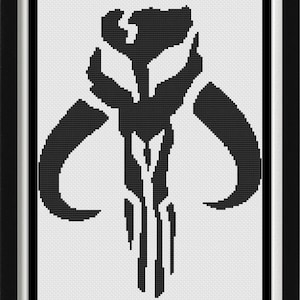 May include: A framed cross-stitch pattern featuring a black Mythosaur skull symbol centered on a white background. Above and below the central icon are lines of black text written in the Aurebesh script, all enclosed within a simple black frame.
