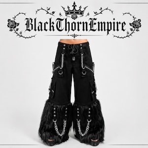 Puede incluir: Pantalones cargo negros con múltiples bolsillos, cremalleras y detalles de cadena plateada. Los pantalones tienen un ribete de piel sintética en los tobillos y una cintura con cordón. El texto "BlackThornEmpire" se muestra en la parte superior.