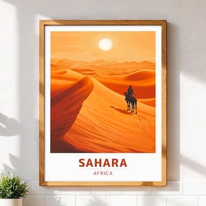 May include: A framed art print depicting a desert scene with a person riding a camel. The artwork features a warm color palette of oranges and yellows, with the sun high in the sky. The text "SAHARA AFRICA" is displayed at the bottom.
