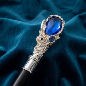 Può includere: Un bastone da passeggio con un manico color argento dal design strutturato e organico. Il manico è decorato con una grande pietra preziosa blu intenso sfaccettata di forma ovale sulla parte superiore e un piccolo accento di pietra blu rotonda.